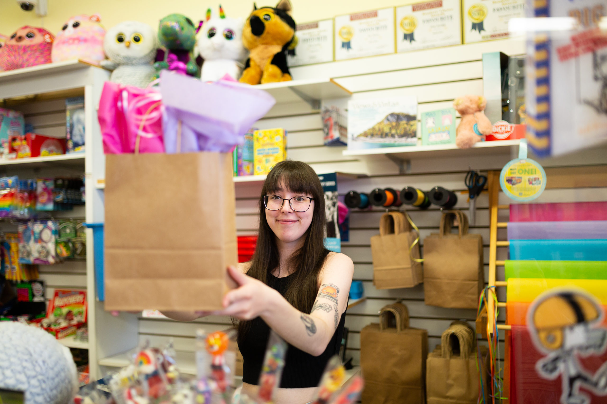Staff at Minds Alive toy store in Collingwood holds up a wrapped gift.