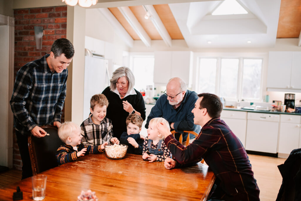 Three generations enjoying popcorn in their family kitchen during candid family photography session in Collingwood