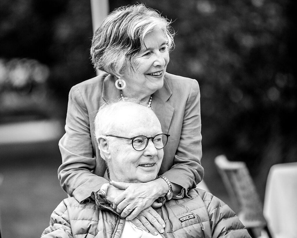 Grandparents from extended family embracing and looking at their family during outdoor family photo session near Collingwood Ontario