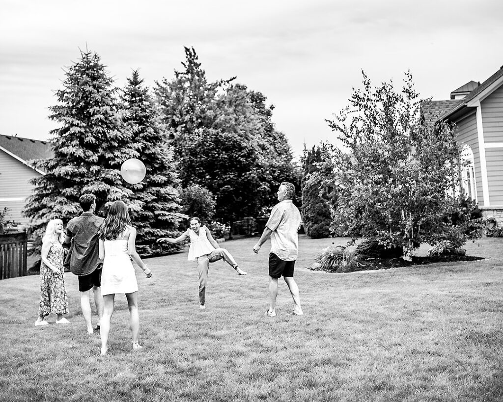 Family laughing and playing with a ball together during outdoor family photo session near Collingwood Ontario