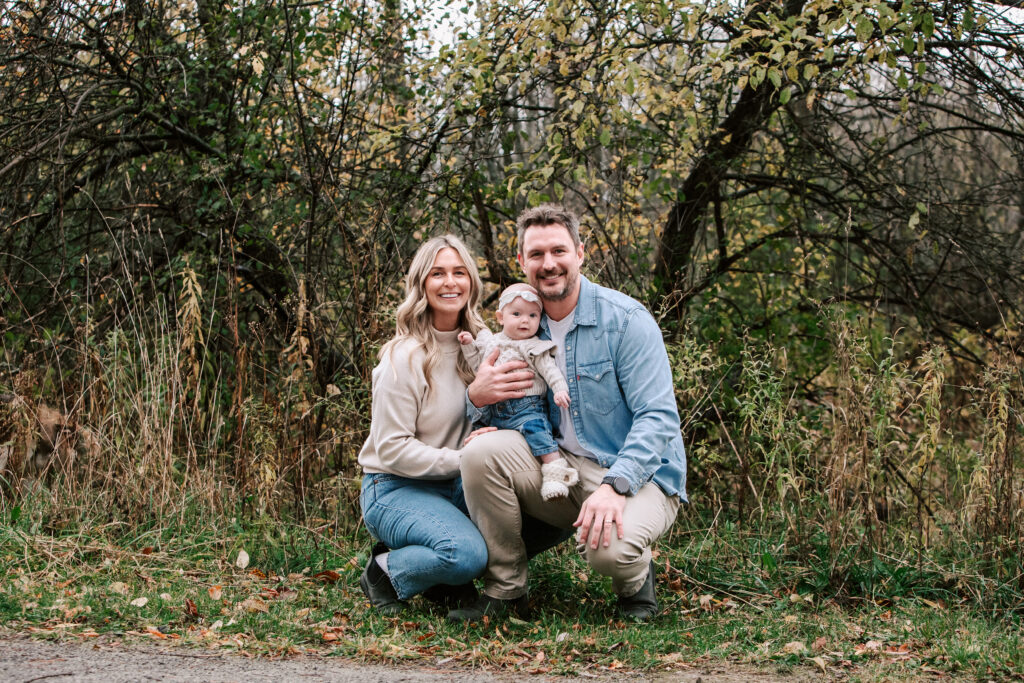 Mom, Dad, and baby girl sitting and smiling during a family mini session in Collingwood, Ontario.
